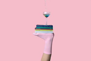 Self-Help books stacked on top of a person's feet wearing pink socks